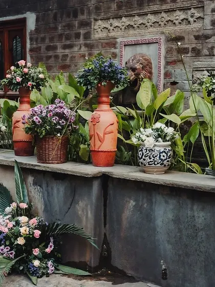 A collection of potted flowers and floral arrangements, adding color and life to a stone ledge.