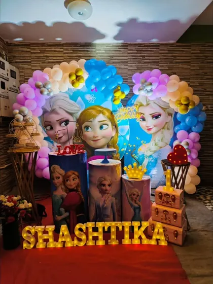 Let it go with our Frozen themed party decor. This setup for Shashtika's first birthday features Elsa, Anna, and Olaf with a blue and purple balloon arch that looks like a winter wonderland.