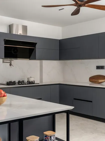 This modern U-shaped kitchen is designed for ultimate functionality. We used a combination of matte grey cabinets and a marble-patterned backsplash for a sleek, contemporary look. The space includes a small island for extra prep area and is equipped with a built-in oven and chimney hood.
