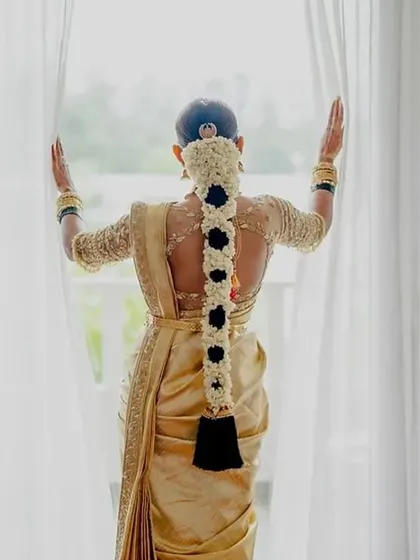 A beautiful back shot of the bride. Her custom blouse features intricate embroidery, and her hair is adorned with traditional jasmine flowers, completing her classic South Indian bridal look.