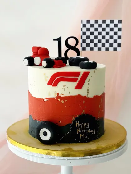 A Formula 1 themed cake for an 18th birthday. It features the F1 logo, a race car, tires, and a checkered flag, perfect for a racing fan.