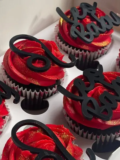 A closer look at the Leo-themed chocolate cupcakes. The base is a moist chocolate cake with indulgent ganache, topped with bold red buttercream and a dash of gold glitter.