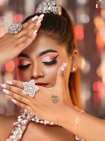 This creative close-up highlights the dramatic eye makeup and the perfectly manicured nails, showing attention to every detail.