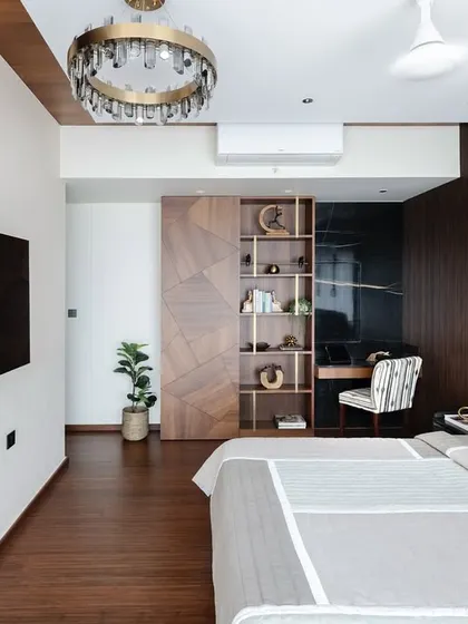 A wider view of the master bedroom with dark wood finishes, showing the TV mounted on a fluted panel wall and the seamless flow of the design.