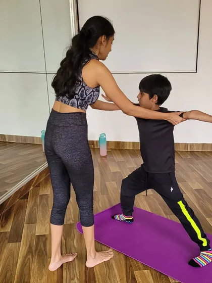 Correcting alignment for a young warrior. My hands on approach ensures children learn poses safely and effectively, building a strong foundation for their practice.