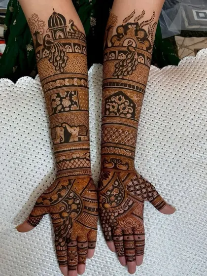 A full-arm design packed with traditional elements. It includes peacocks, elephants, and architectural domes, creating a rich and dense pattern.