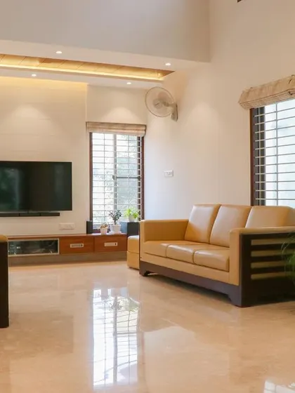 The living room in 'Isha-Vaasyam', an artist's abode, features clean lines, warm wood furniture, and ample natural light for a calm and creative environment.