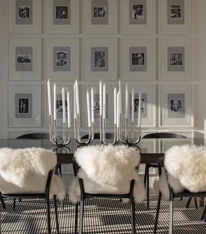 A chic, contemporary dining room with a gallery wall of framed photos and chairs draped with faux fur for a touch of texture and luxury.