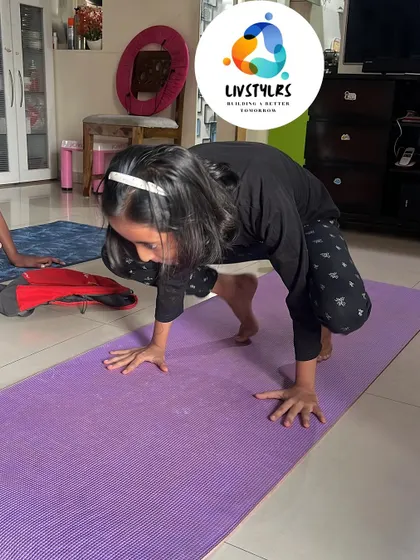 A young girl practices Bakasana (Crow Pose), a challenging arm balance that builds immense upper body strength and focus.