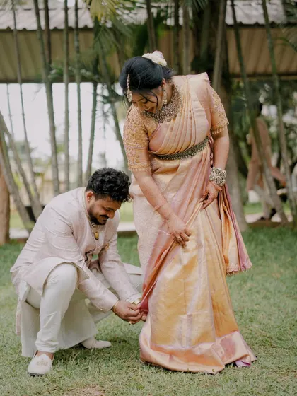 A sweet, candid moment of the groom helping his bride with her saree. It’s these small, thoughtful gestures that often tell the biggest stories about a couple's love and care for each other.