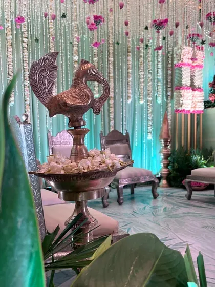 A close-up of a traditional silver peacock lamp, a beautiful element in a sacred ceremony setup. The details honor heritage while contributing to the overall aesthetic.