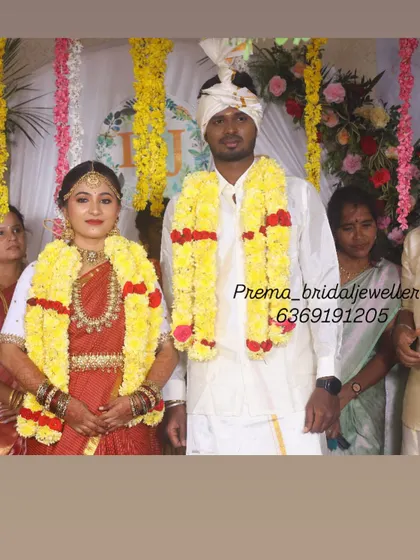 A beautiful moment from a traditional wedding ceremony. The couple is adorned with yellow flower garlands, and the bride is wearing a lovely temple jewellery set.