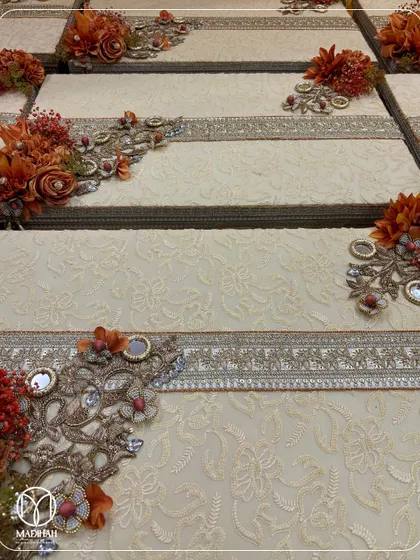 A close-up of the detailed craftsmanship on my trousseau boxes. The rich, textured fabric is adorned with a band of traditional silver embroidery and a corner piece of flowers, mirrors, and crystals.