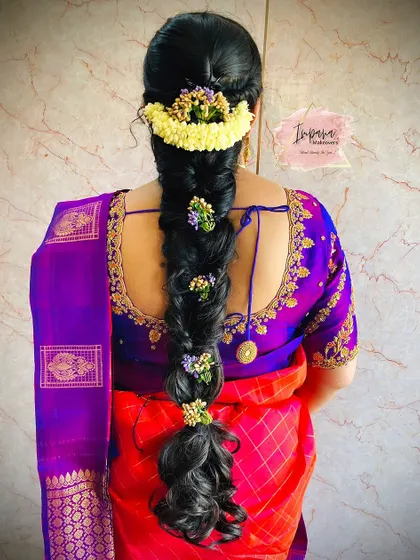 A voluminous messy braid for a housewarming ceremony. This hairstyle uses fresh flowers and extensions to create a full and festive look.