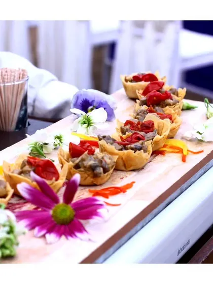 A platter of vegetarian canapés in crisp wonton cups, garnished with edible flowers for a beautiful presentation.