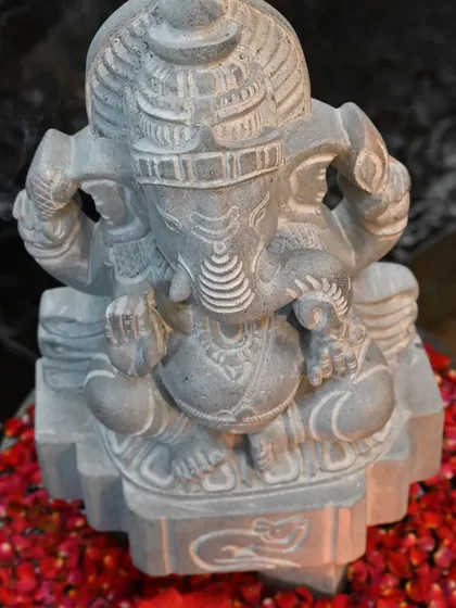 Another view of our Buddhividhata Ganesha, set against a backdrop of red flower petals, emphasizing its divine presence.