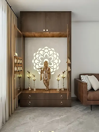 A lovely pooja unit designed to fit perfectly next to a living room sofa. The doors open to reveal a serene space for prayer, complete with a backlit mandala and storage drawers.
