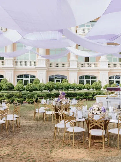 A wide shot of the outdoor dining area, with flowing lavender and white drapes creating a beautiful canopy overhead.