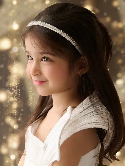 A classic, sparkling portrait of a young girl. The soft focus and golden bokeh background add a touch of magic, highlighting her bright eyes and gentle smile.