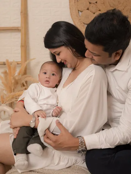A classic portrait of new parents holding their baby, a timeless image of a family complete.