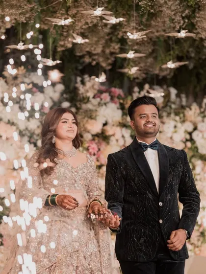 A grand entrance for the reception. Surrounded by sparklers, the couple looks radiant. Her makeup is designed to be the center of attention, with a glow that rivals the fireworks.
