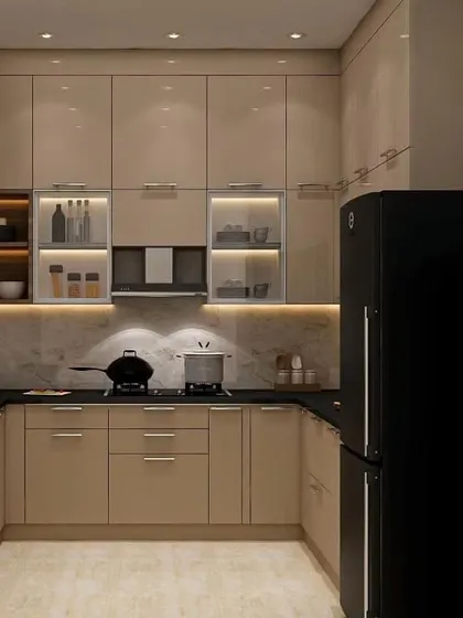 This elegant U-shaped kitchen uses a calming beige color for the high-gloss cabinets. The black countertop and black refrigerator create a striking contrast, and the lit glass cabinets add a touch of sophistication.