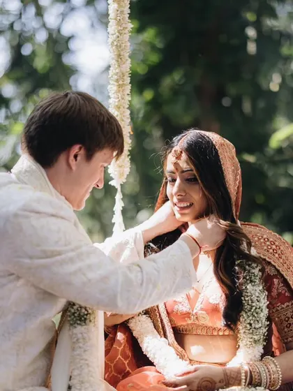 An intimate moment during the ceremony. The groom's simple ivory sherwani allows the bride's stunning rust and gold lehenga to take center stage, while still feeling connected.