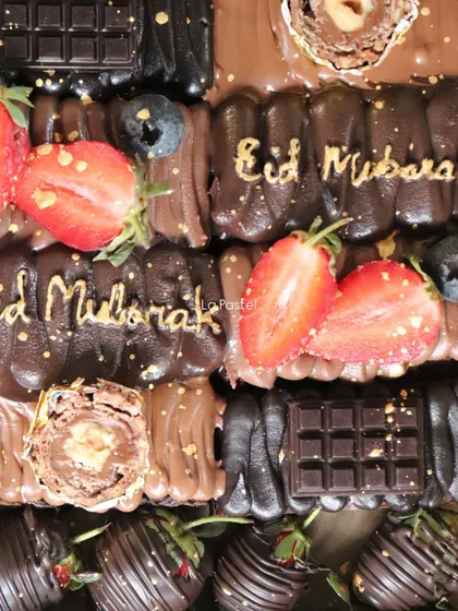 A close-up of my Eid chocolate slab cake, decorated with fresh strawberries, blueberries, and "Eid Mubarak" in gold script.