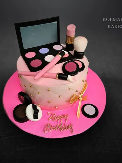 This pink mango cake is decorated with a variety of edible makeup items. It includes a fondant eyeshadow palette, lipstick, brushes, and compacts for a fun and glamorous birthday.