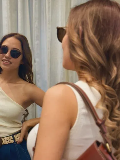 A closer look at a client's reflection as she admires her new hair. The sunglasses add a cool vibe, but the star of the show is the beautifully styled, healthy-looking brown hair.