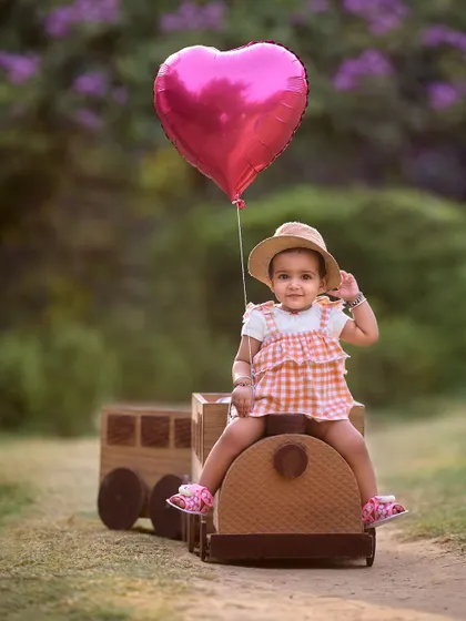 A stylish little passenger on the birthday express. The combination of a cute outfit, a fun prop like this wooden train, and a heart-shaped balloon makes for a perfect pre-birthday portrait.