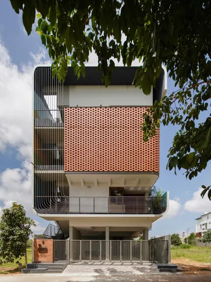 The front facade of 'House Belaku', where the brick screen, vertical fins, and curved balconies come together to form a cohesive and modern architectural statement.