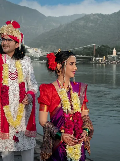A classic portrait of the Marathi bride and groom by the Ganga, with the iconic Laxman Jhula bridge in the background.