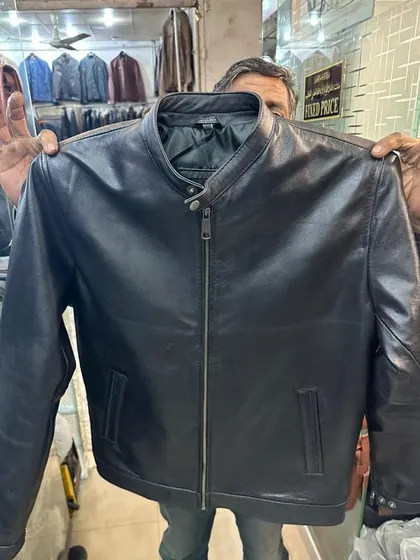 Holding up a classic black leather jacket to show its full design. This style is a staple and the quality from my Karachi source is 'mmg elok'.