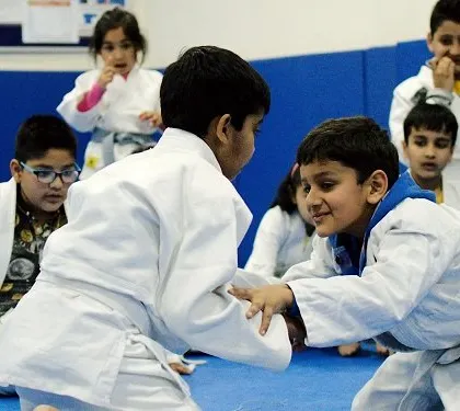 Young students learning the fundamentals of Judo. They learn how to engage with a partner respectfully while practicing essential grappling skills.