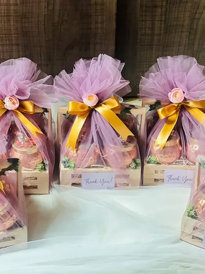 A bulk order of corporate gift hampers, beautifully wrapped in lavender net with gold ribbons. This presentation is perfect for large-scale corporate events or holiday gifting.