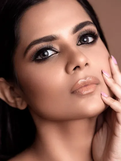 A close-up beauty portrait with a focus on glossy lips and smoky eyes. The lighting is crafted to create a soft, flawless skin texture, showcasing the result of professional retouching.