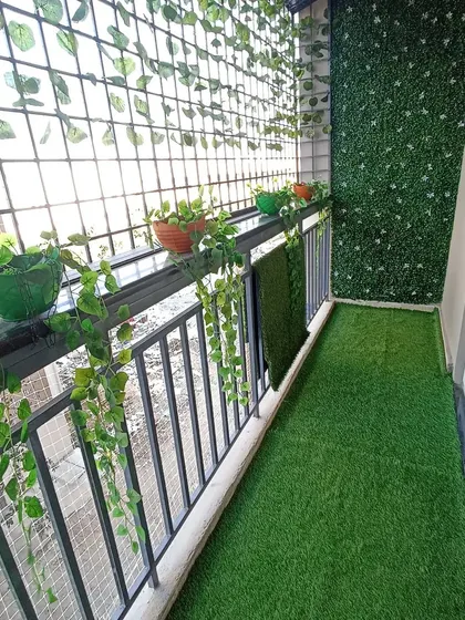 Another angle of a mixed-material balcony garden. The combination of artificial turf, a green wall, and hanging plants creates a layered, textured look that is both beautiful and practical.