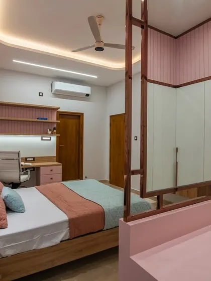 A dual-purpose dressing table and partition in a daughter's bedroom, with a mirror on the back. This clever design separates the sleeping area from the study nook, which features a pink and wood desk.