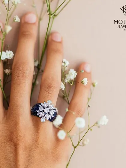 A beautiful floral cluster of diamonds sits atop a band of deep blue sapphires. This image, with its soft floral background, evokes a sense of romance and natural beauty.