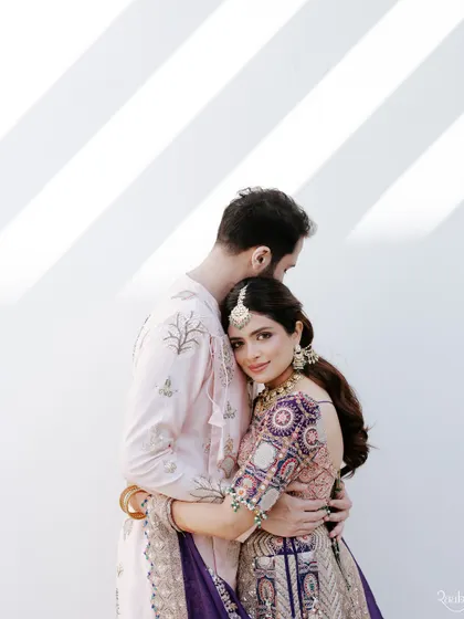 A tender embrace against a white wall with diagonal shadows, a simple yet powerful portrait from the Doha wedding.