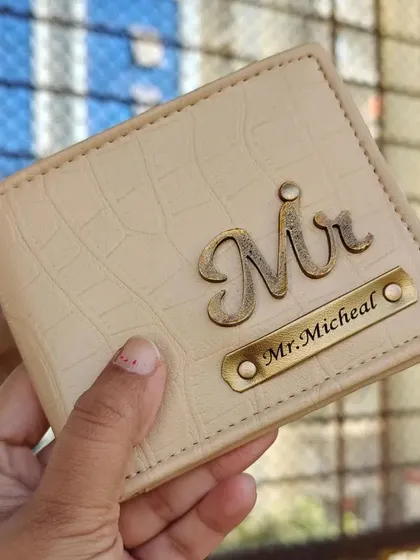 This cream-colored wallet in a crocodile texture features a "Mr." charm and a custom nameplate, offering a sophisticated and unique look.