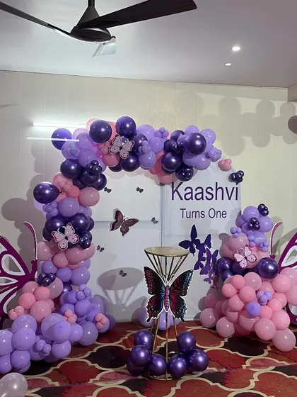 A stunning Butterfly theme for a first birthday, with large wing cutouts framing the balloon-decorated backdrop.