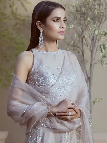 This portrait-style campaign shot highlights the intricate beadwork on the blouse and the sheer fabric of the dupatta. The focus is on the texture and detail that make this designer piece special.