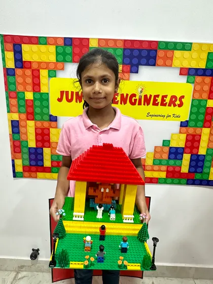 A young girl holds her beautifully constructed LEGO temple pandal, complete with figures, created during our Ganpati workshop.