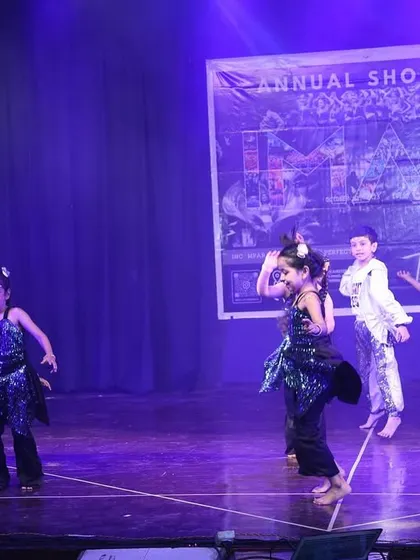 Our junior performers dancing with joy under the purple stage lights.