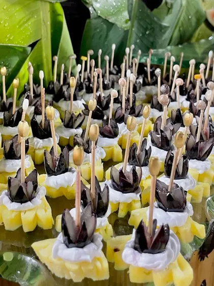 An imaginative fruit skewer with pineapple and black grapes, designed to look like a flower.
