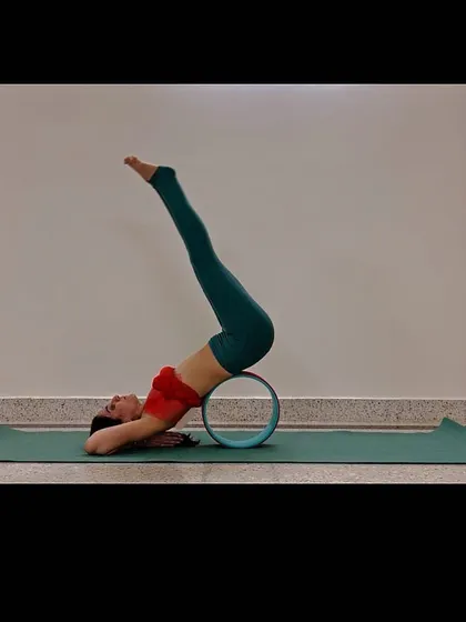 Shoulder stand style backbend with a yoga wheel under the hips.