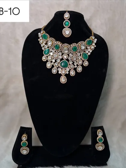 This elegant polki and emerald green stone choker, set B-10, is perfect for a bride or wedding guest. It comes with simple, matching earrings and a maang tikka.