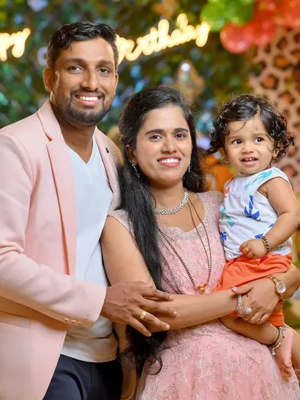 A happy family of three posing for a photo at their child's birthday celebration. We work to make everyone feel comfortable, resulting in relaxed and genuine family portraits.
